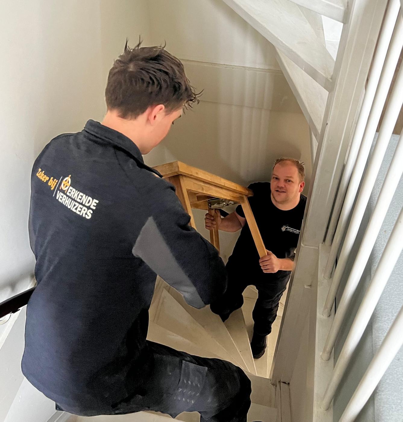 Verhuizers van Jacobs Heteren dragen een meubelstuk de trap op
